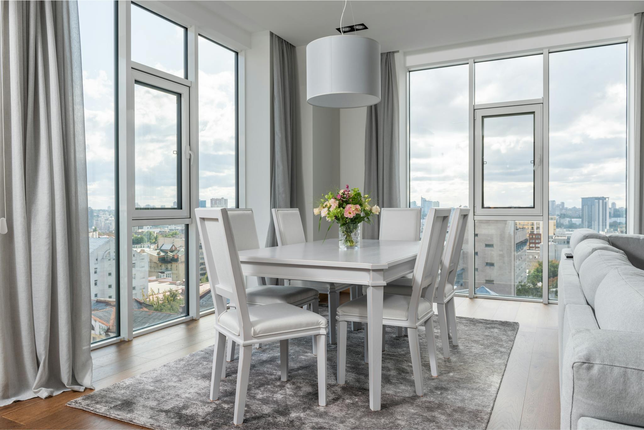 A contemporary dining room with cityscape views, elegant design, and a floral centerpiece.